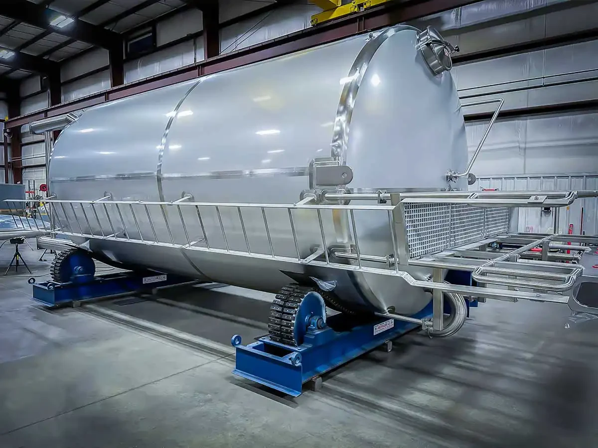 A tall cylindrical industrial storage tank with a vertical safety ladder mounted to the side. The tank is constructed of stainless steel and is designed for safe access and maintenance at height.