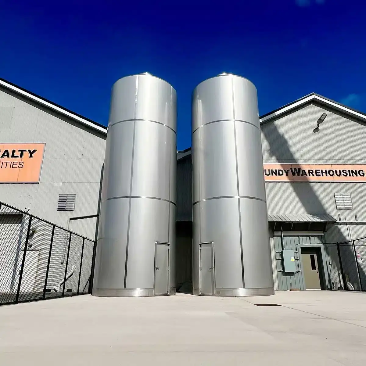 two stainless steel silos installed upright outdoors